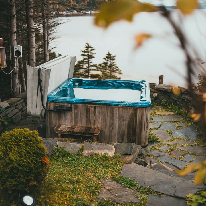Weathered wooden hot tub on a backyard stone patio